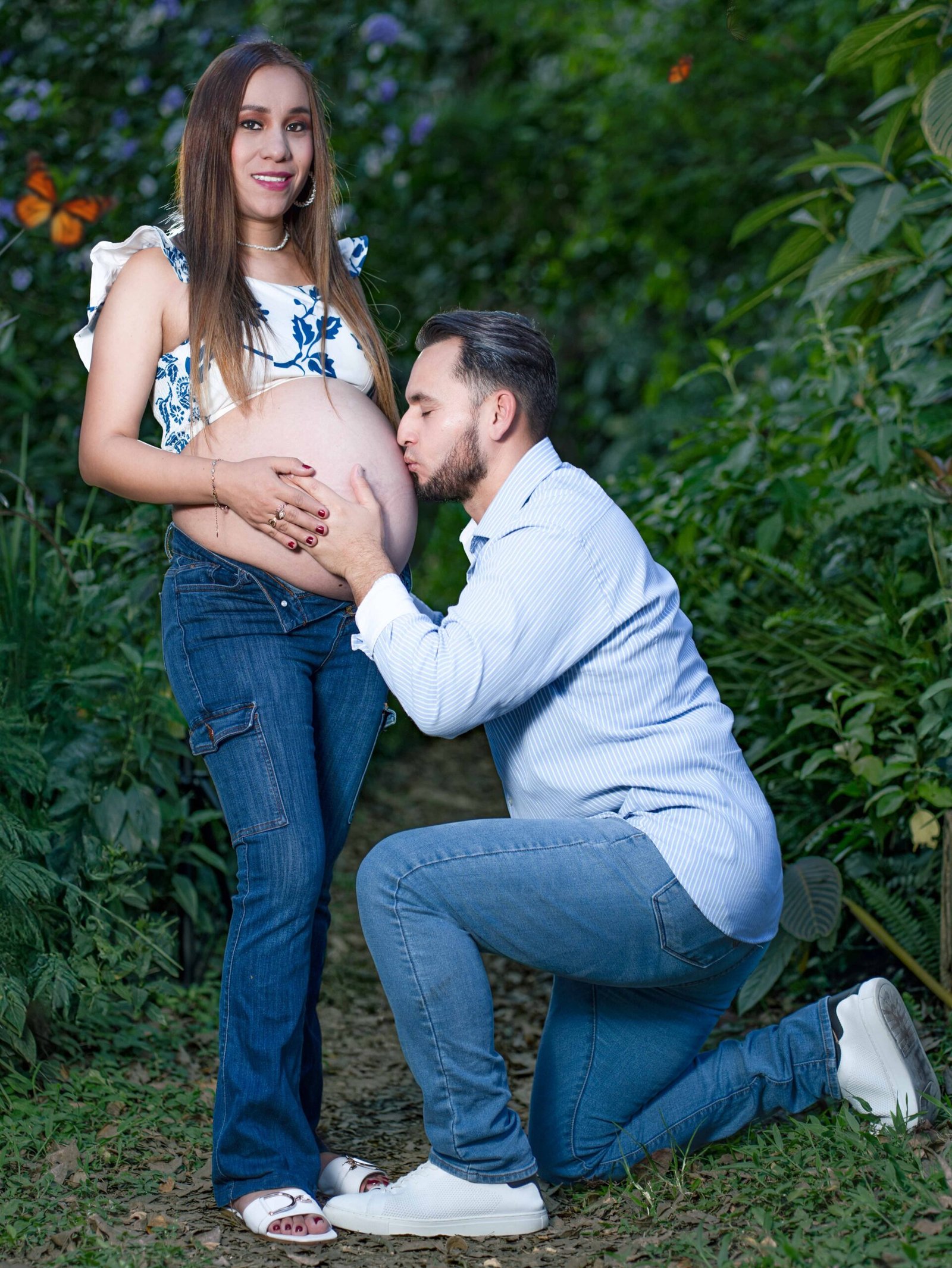 Mujer embarazada sonriendo con su esposo durante sesión de maternidad en exterior